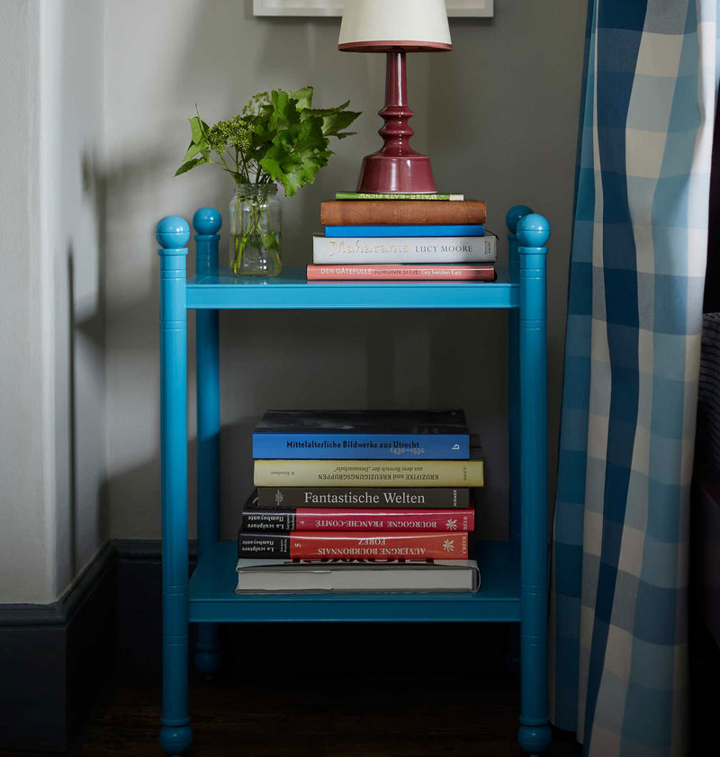 Blue Revive bedside table with books, a table lamp, and a potted plant, designed by Nicola Harding & Co for a modern and serene bedroom.