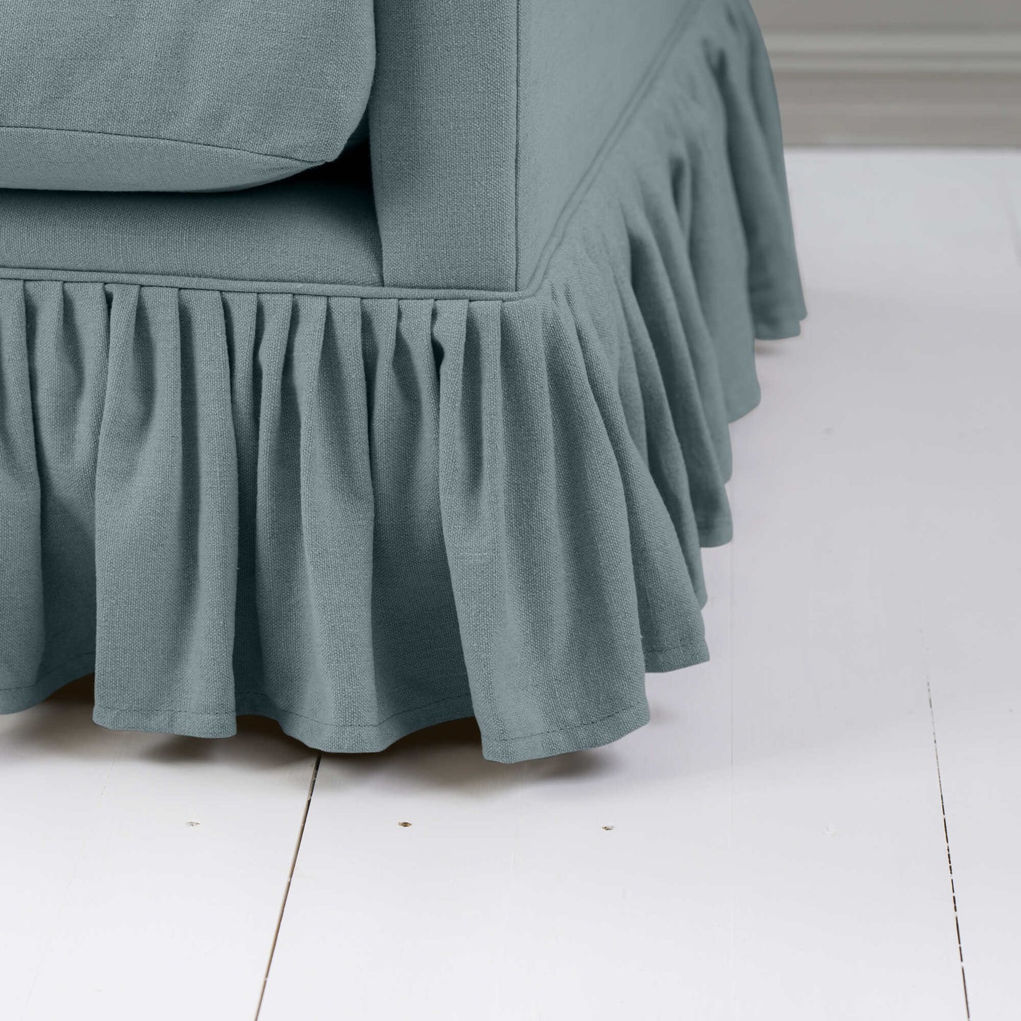 Detailed shot of a blue couch with a ruffled skirt.