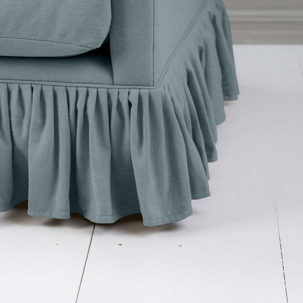  Detailed shot of a blue couch with a ruffled skirt. 