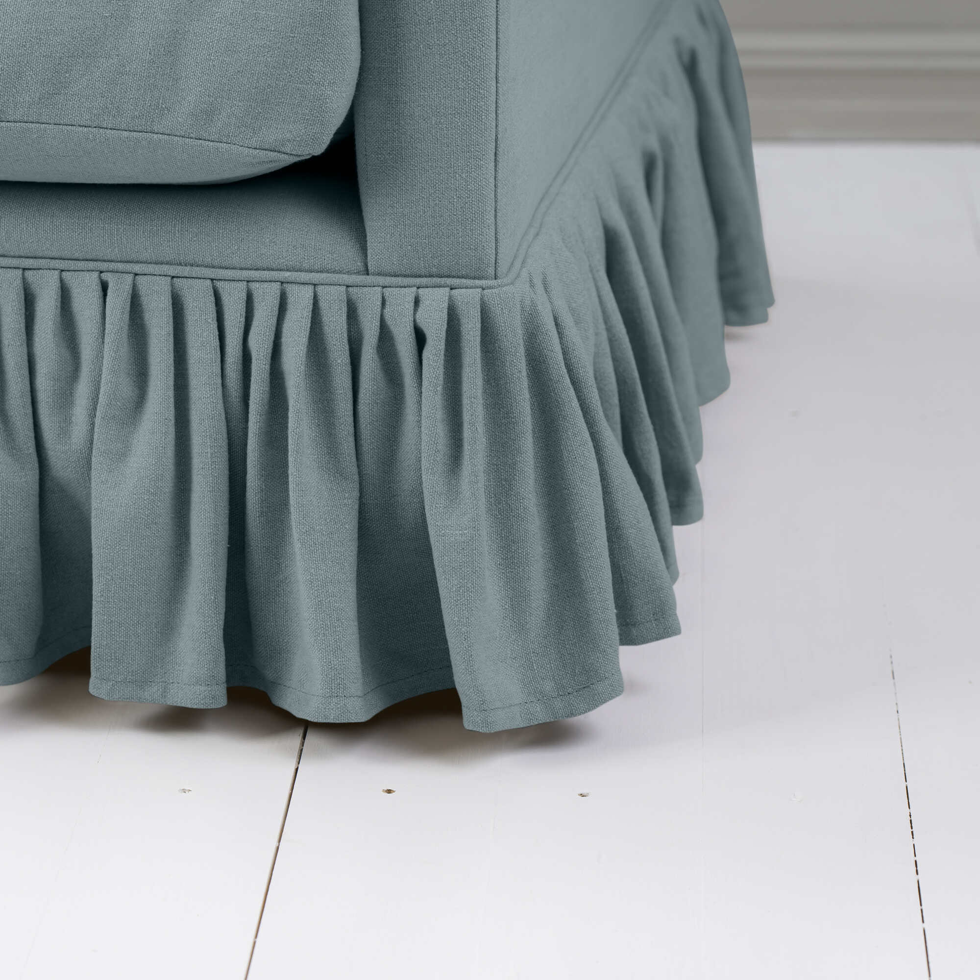  Blue couch with ruffled skirt, close-up view. 