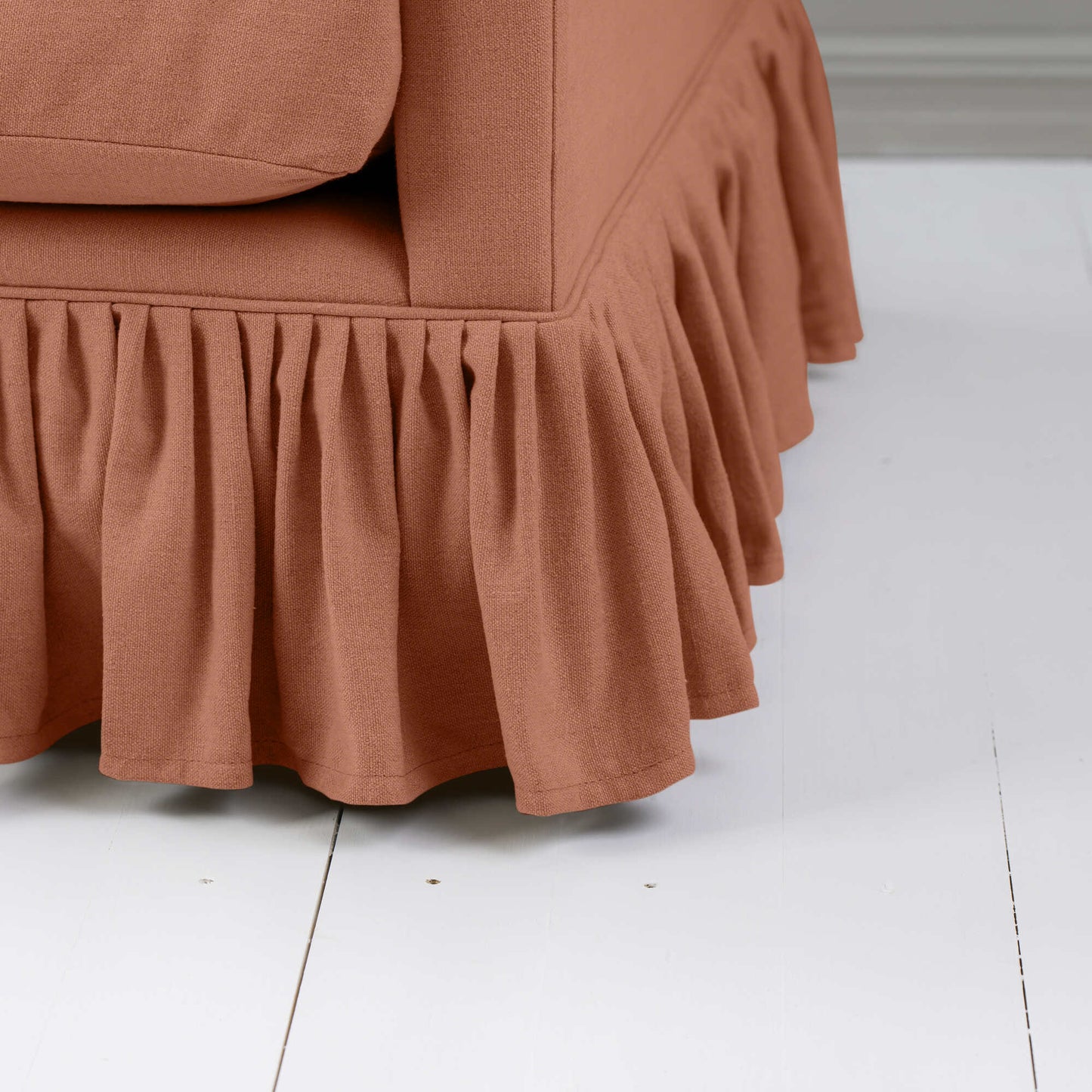 Detailed shot of a orange couch with a ruffled skirt.