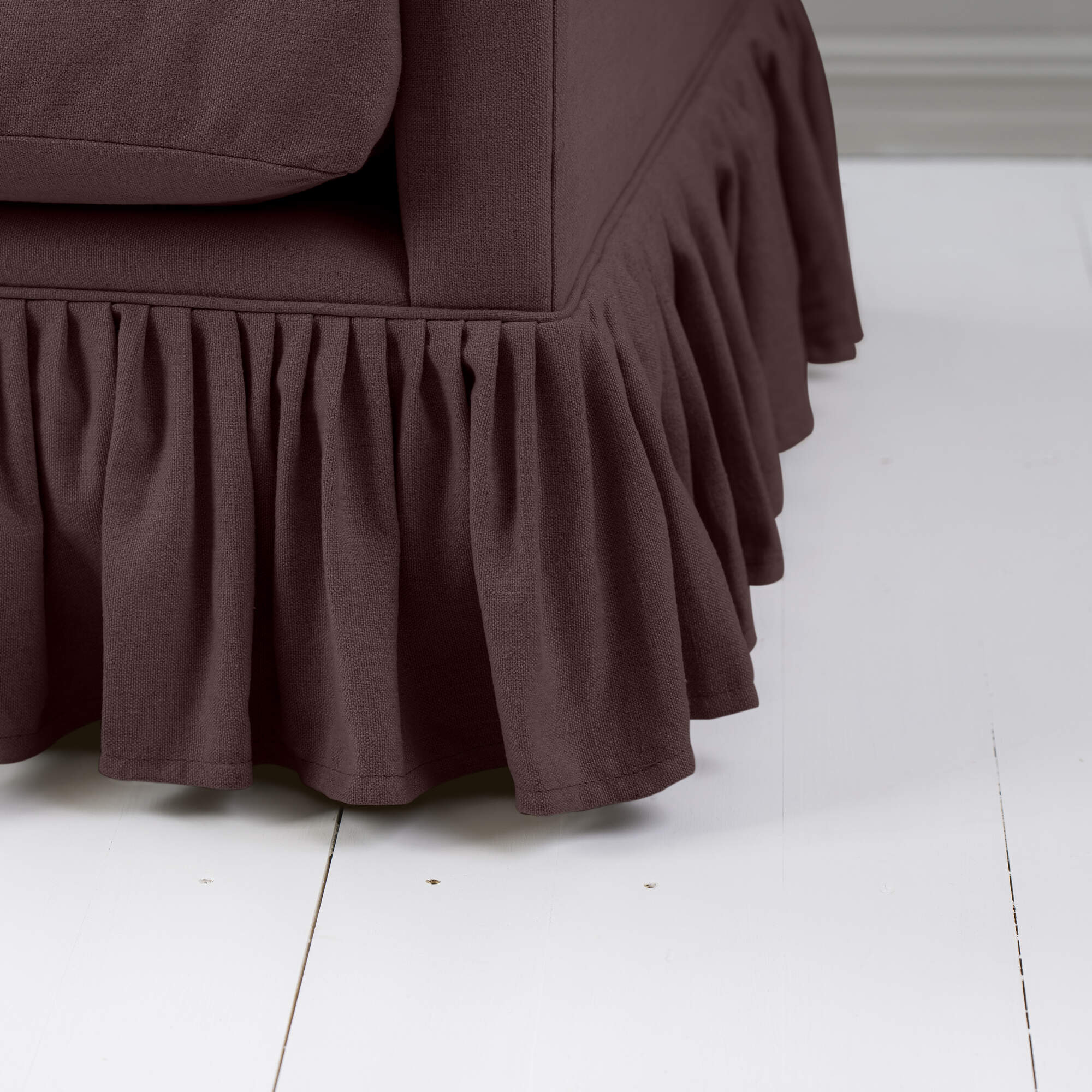  A close-up of a dark brown couch with a ruffled skirt, adding elegance and charm to the overall aesthetic. 