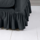  A close-up of a couch with a black ruffled skirt, adding elegance and charm to the furniture. 