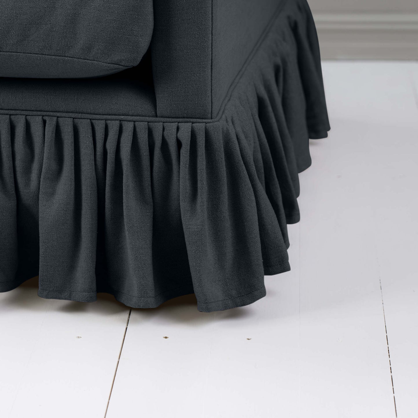 A close-up of a black couch with a decorative ruffled skirt, adding an elegant touch to the overall design.