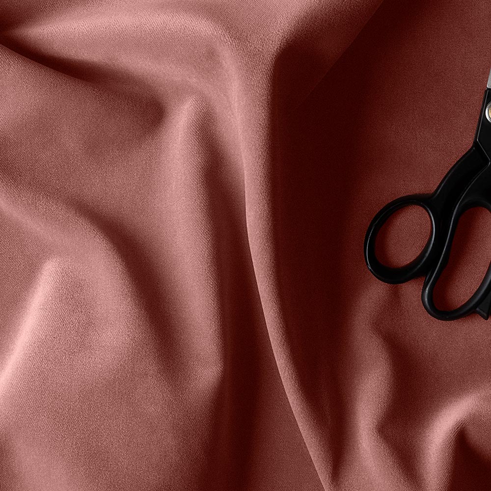 A pair of scissors on a pink fabric.