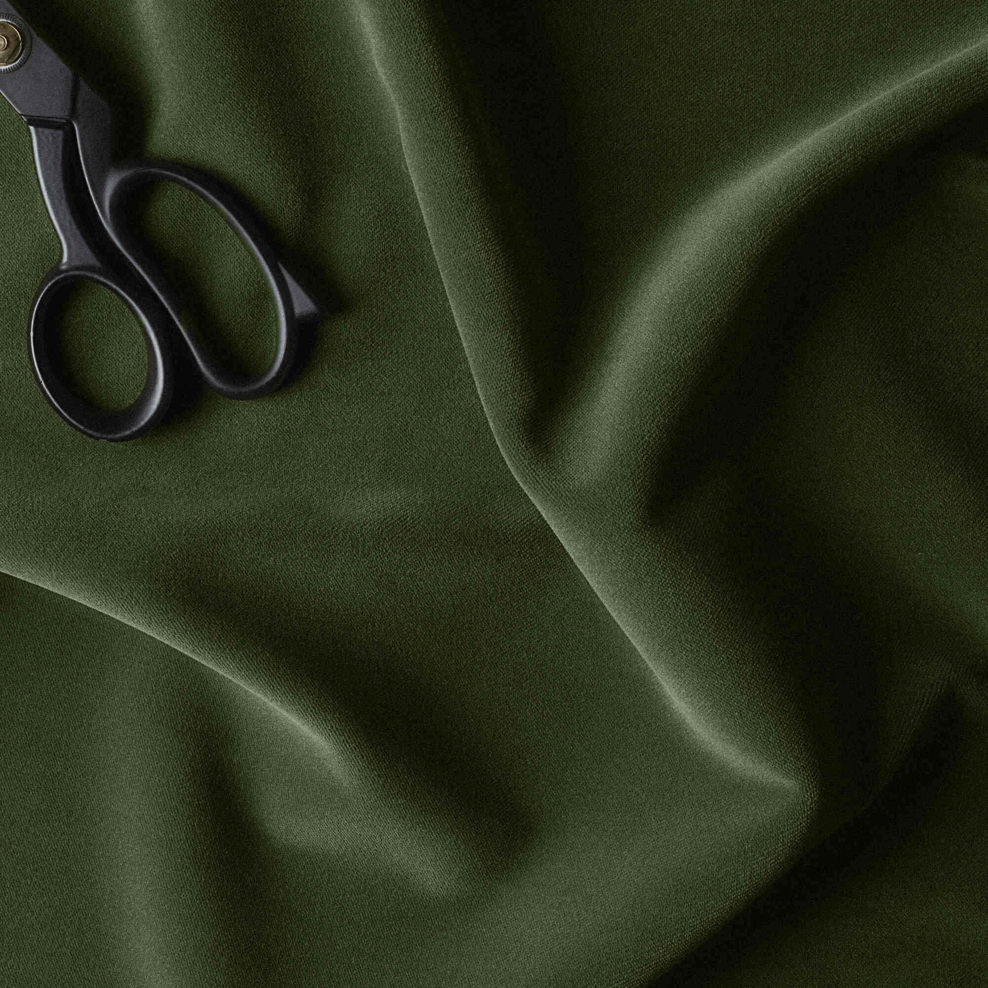  A pair of scissors cutting green fabric. 