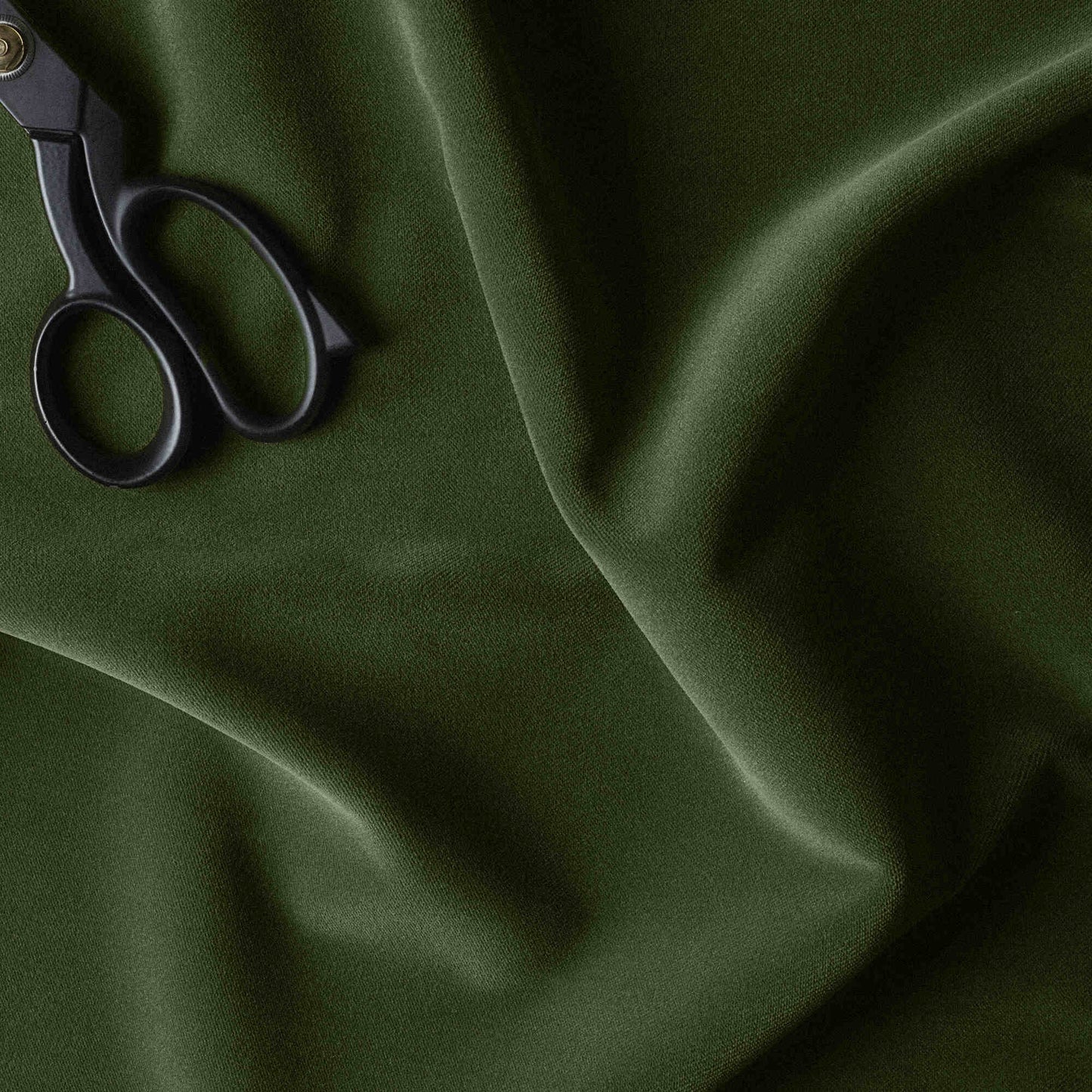 A pair of scissors cutting green fabric.