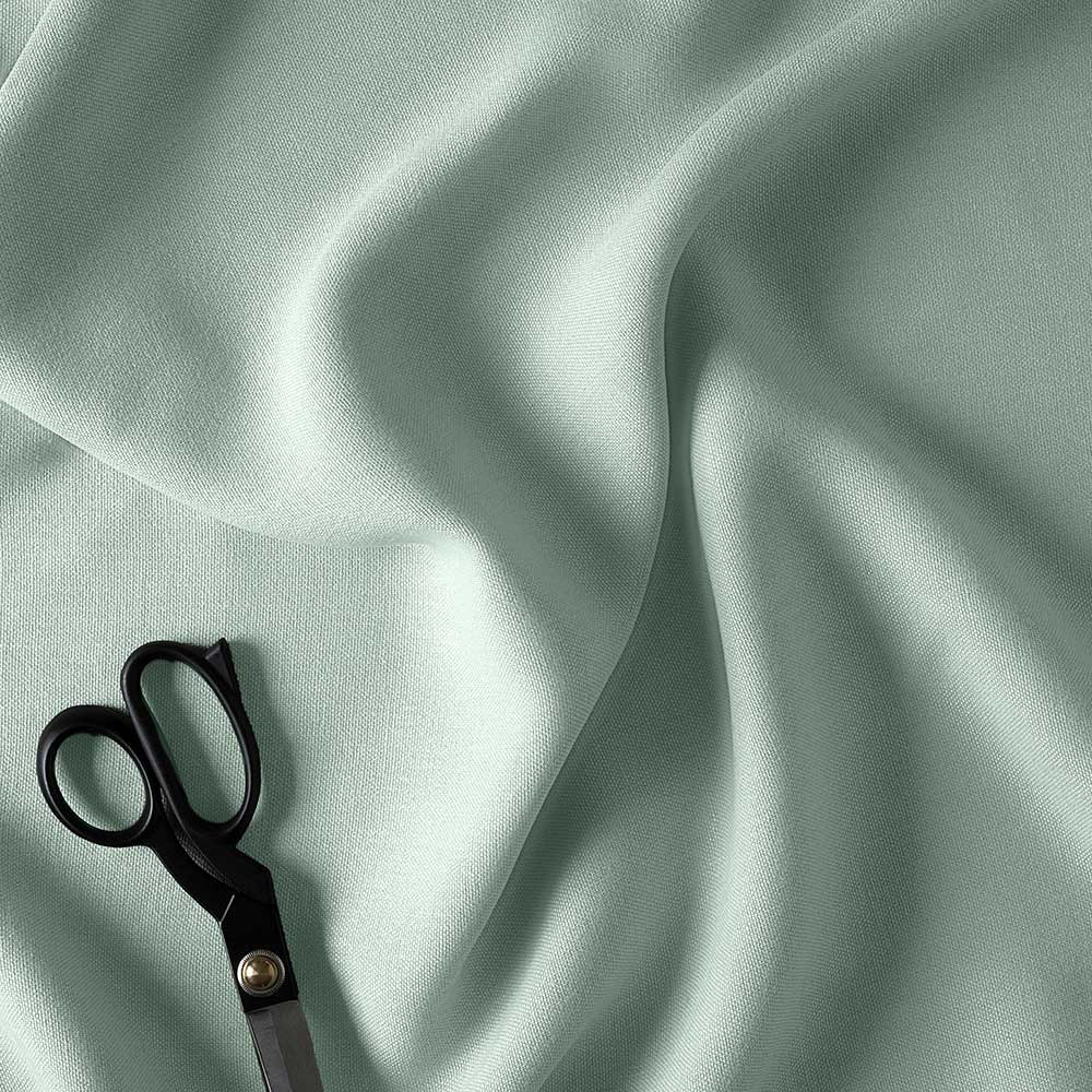 A pair of scissors on a light green fabric.