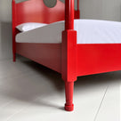  A close up of red canopy bed with crisp white sheets, creating a serene and elegant atmosphere. 