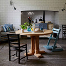  Round dining table in oak, decorated with two chairs, a candle cup, and two beautiful plants placed on the table, in the living room, designed by Nicola Harding. 
