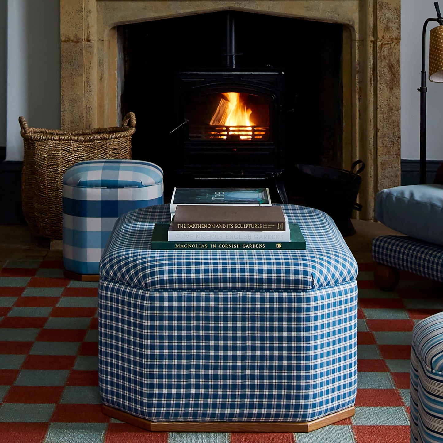 Hither Hexagonal Storage Ottoman with books in front of fireplace in designer living room by Nicola Harding & Co.