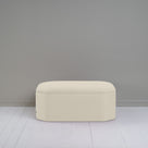  Small white ottoman in room with gray wall, adding cozy touch to modern decor. 