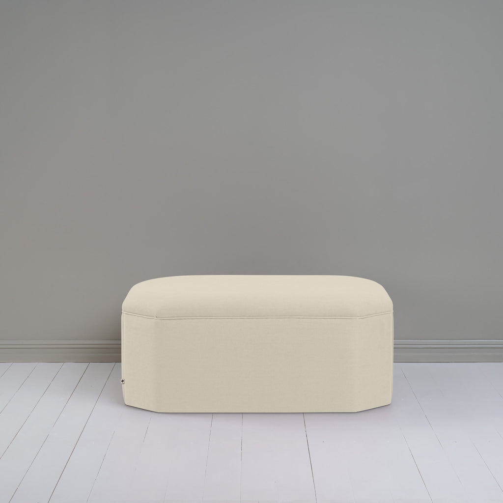  Small white ottoman in room with gray wall, adding cozy touch to modern decor. 