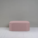  Pink ottoman against gray wall in room. 