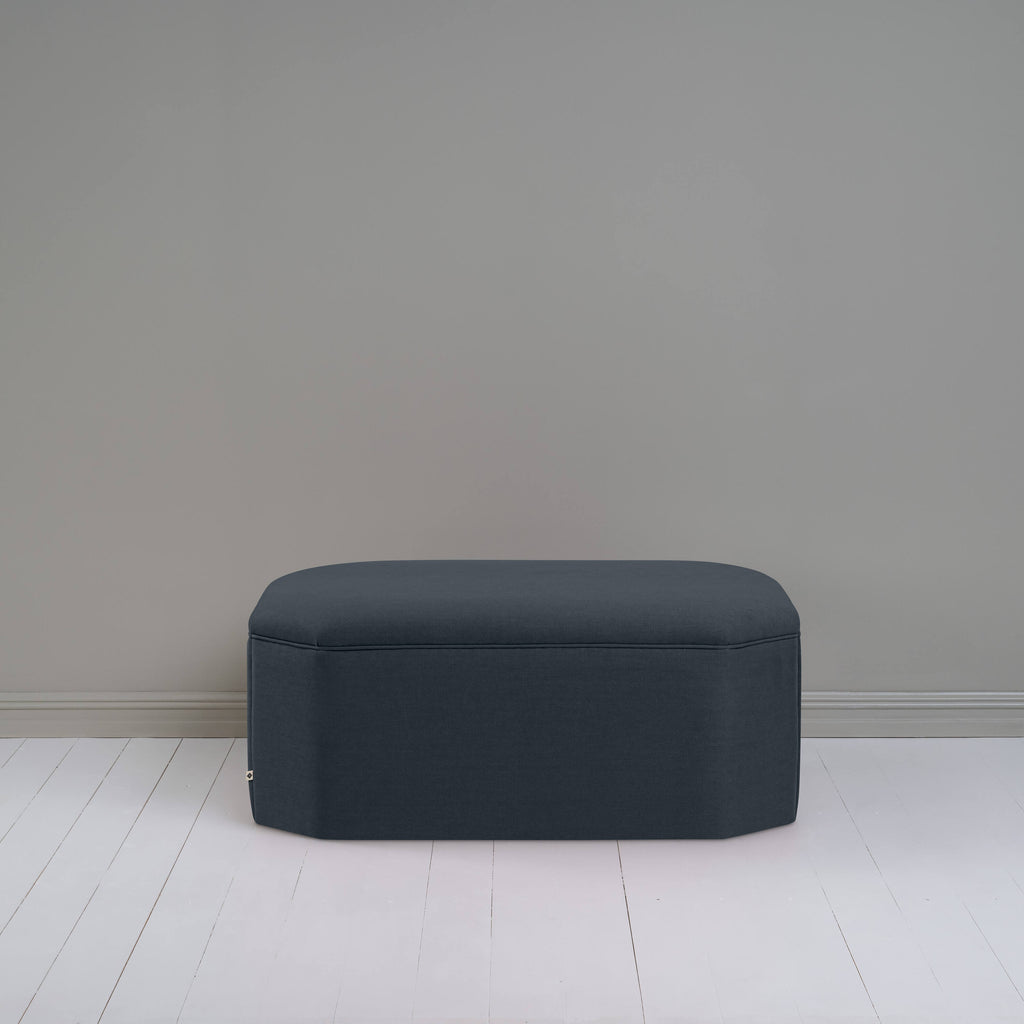  Black ottoman against gray wall in room. 