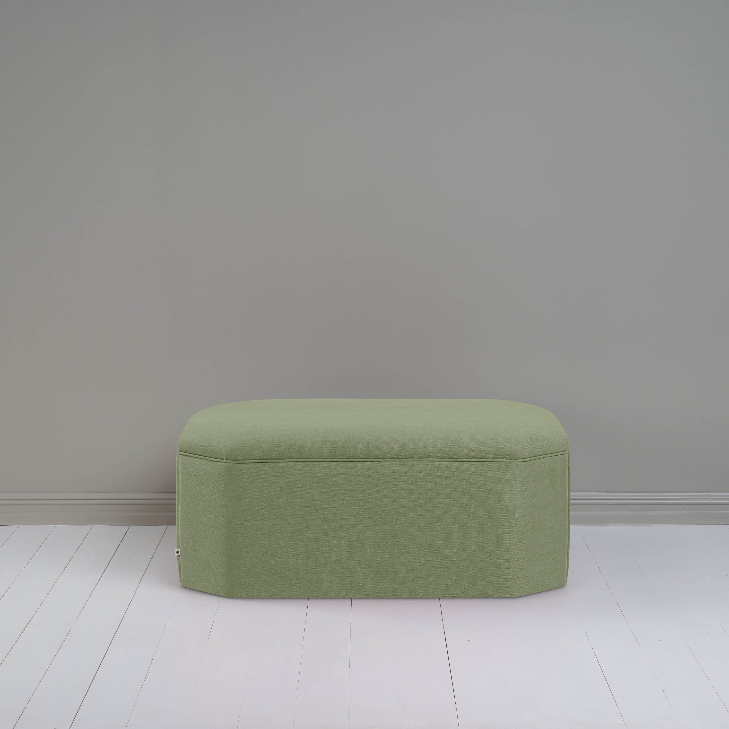  Green ottoman against gray wall in room. 