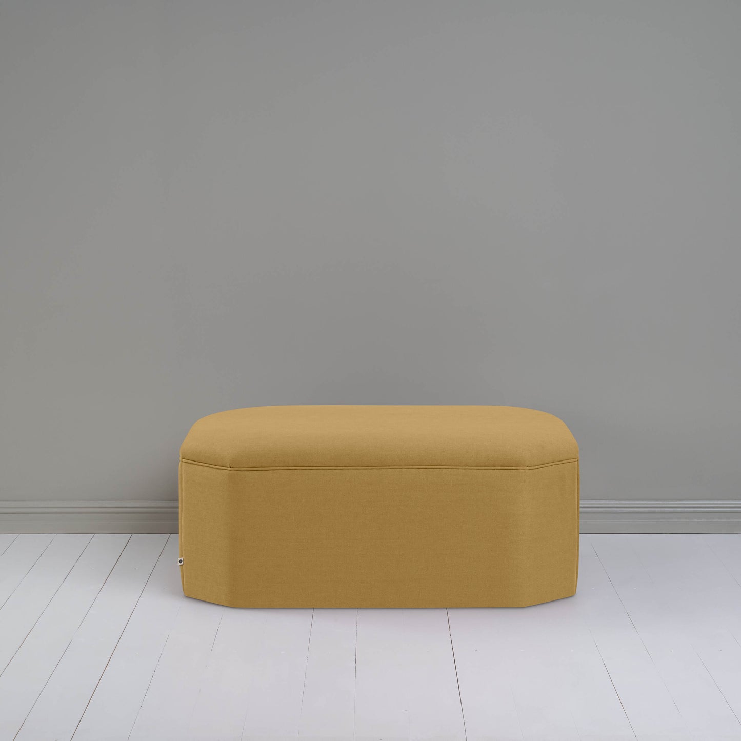 Ottoman against gray wall in room.