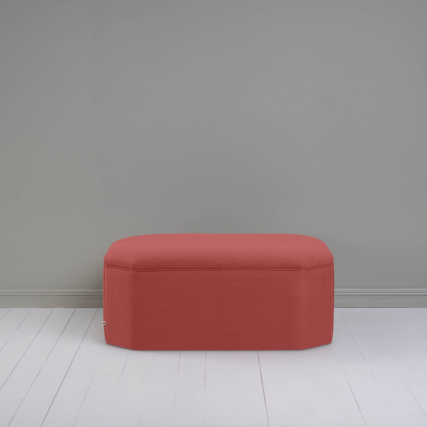 A small red ottoman, perfect for adding a touch of color and comfort to any room.