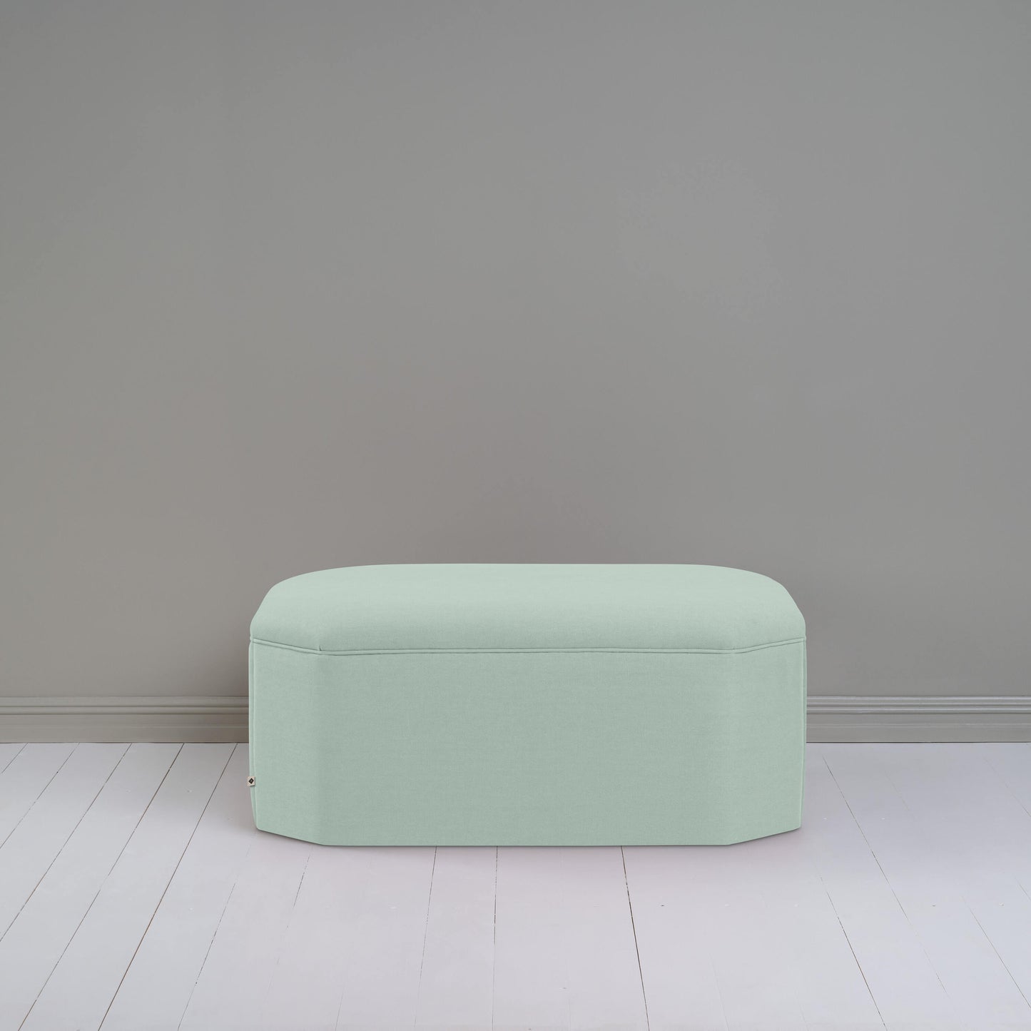 A small light green ottoman, perfect for adding a touch of color and comfort to any room.