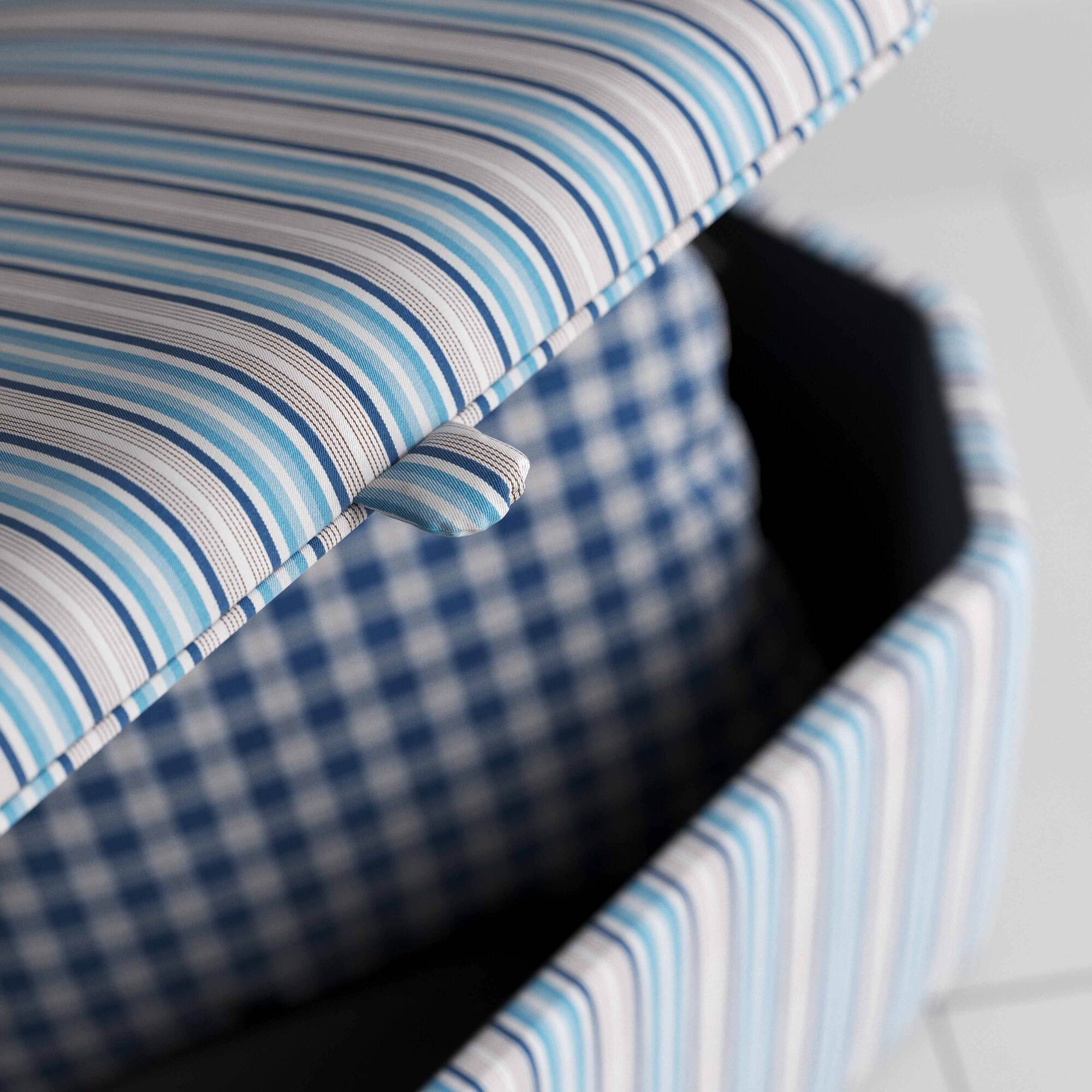  A close up of blue and white striped ottoman on wooden floor. 