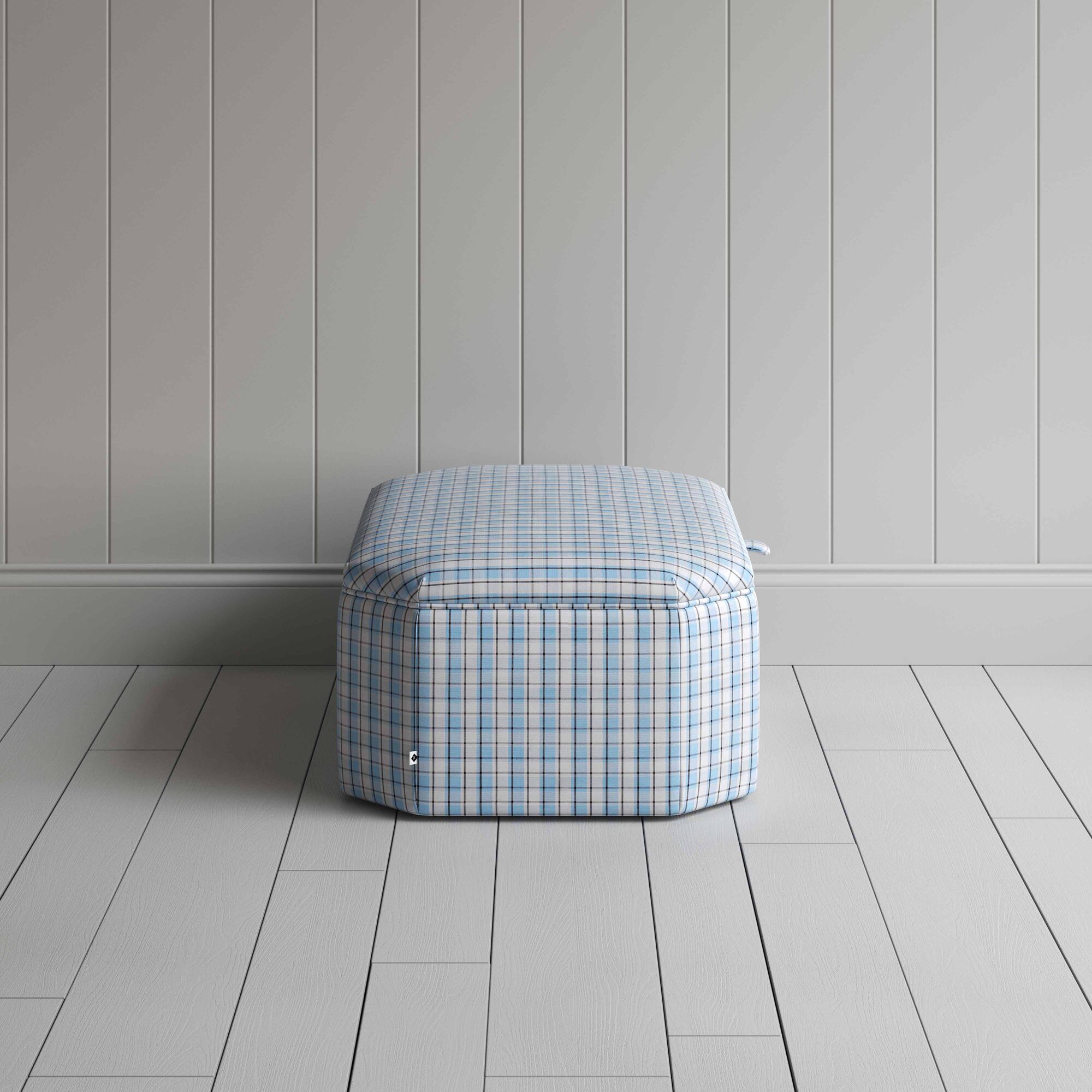  Blue and white checkered ottoman on wooden floor. 