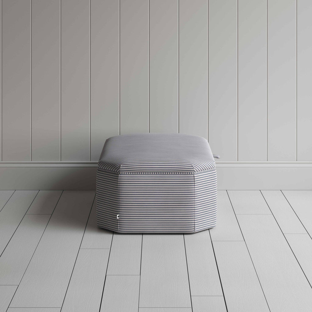  Stylish grey ottoman against white flooring. 