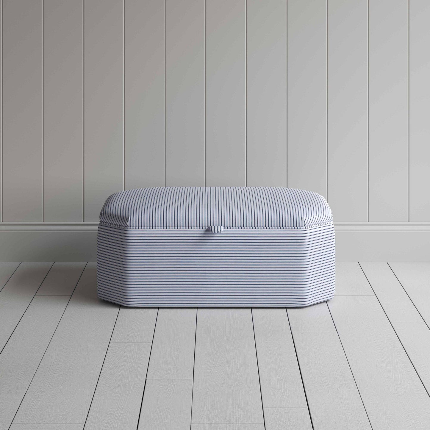 A white and blue striped ottoman on a wooden floor, providing a stylish and practical storage solution.