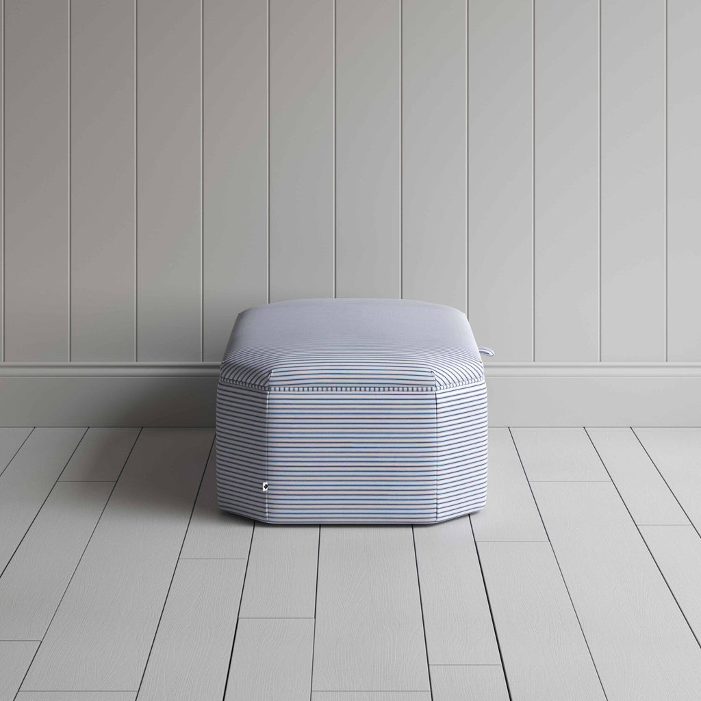  A white and blue striped ottoman on a wooden floor, providing a stylish and practical storage solution. 