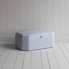  A white and blue striped ottoman on a wooden floor, providing a stylish and practical storage solution. 