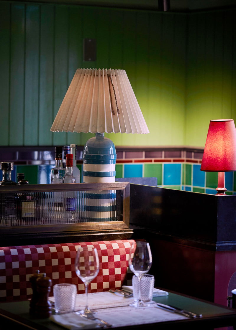 A table with a lamp and a glass of wine, creating a cozy ambiance.