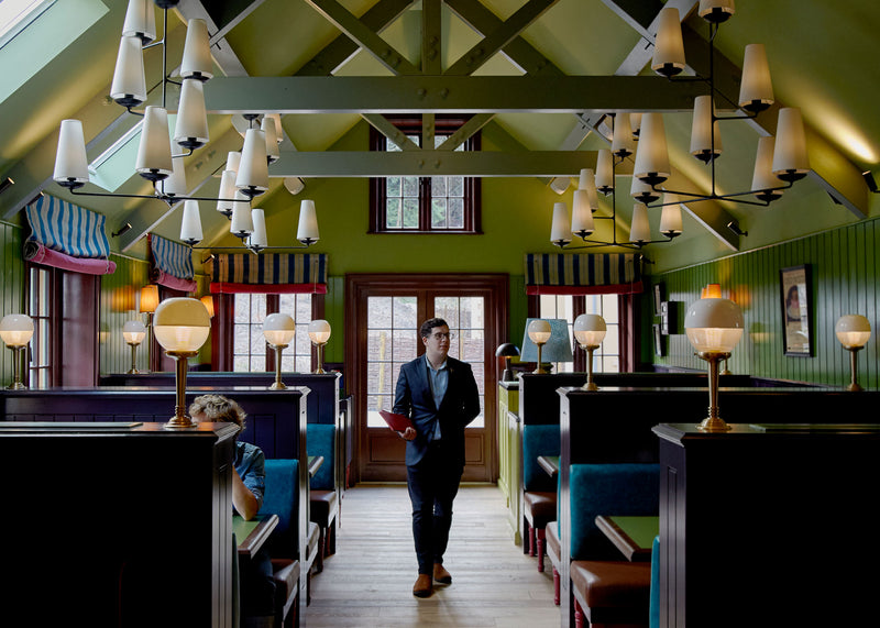 A well-dressed man standing in a restaurant, exuding elegance and sophistication.