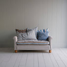  2-seater sofa in Ticking Cotton Chocolate Navy frame with a Regatta Blue seat, complemented by multiple NiX cushions. 