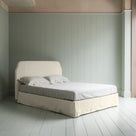  King-size upholstered bed by NiX in laidback linen dove with a kick pleat valance, shown in a complete side view. 