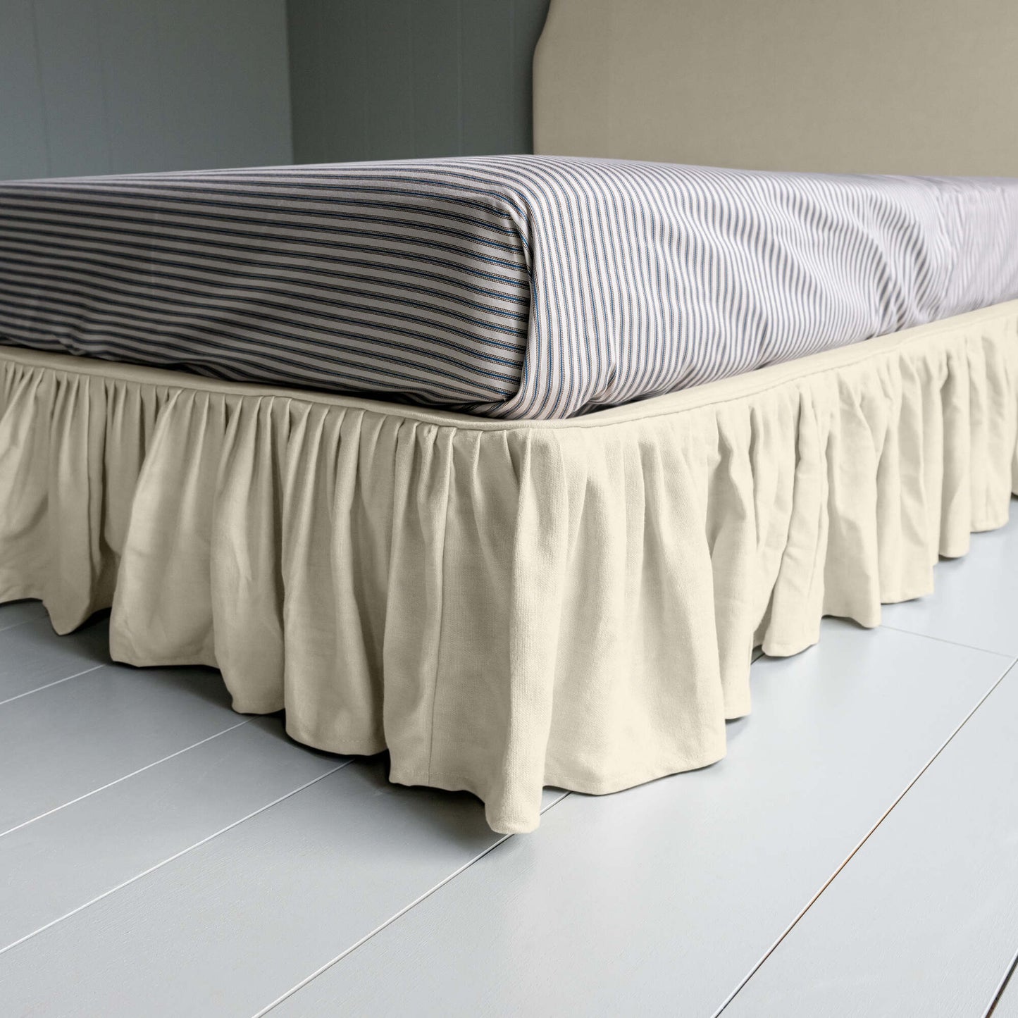 Upholstered Bed in Laidback Linen Dove with a ruffled valance, showcasing the edge design and a neatly tucked-in bedsheet.