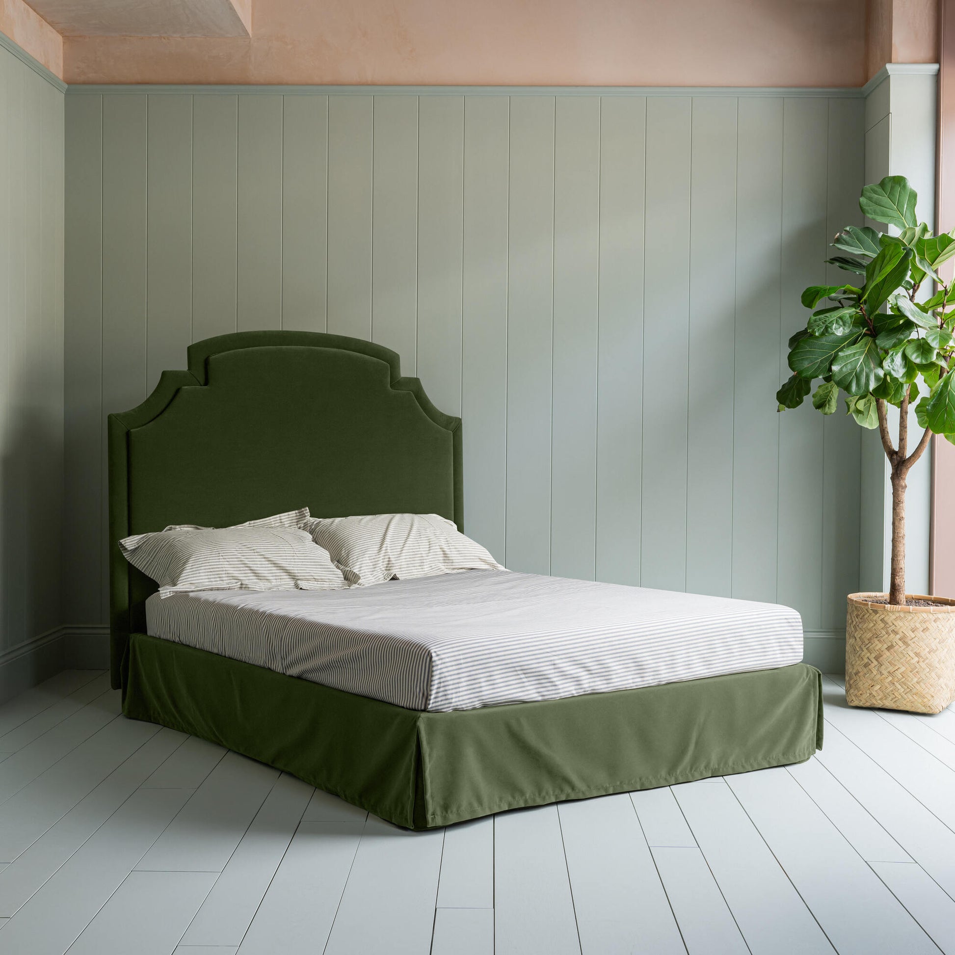 Seventh Heaven Upholstered Bed in Intelligent Velvet Juniper with Kick Pleat Valance complete bed picture with an indoor plant on the left.