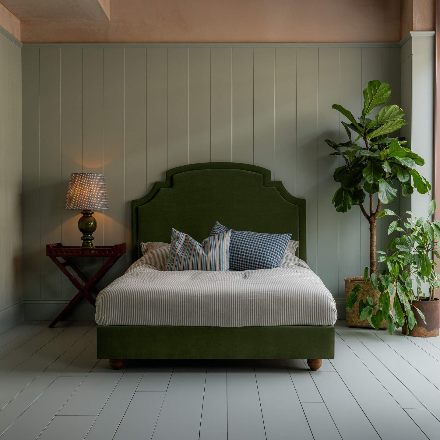 Seventh Heaven Upholstered Bed in Intelligent Velvet Juniper without Valance, accompanied by a side table lamp, pillows, and a blanket.