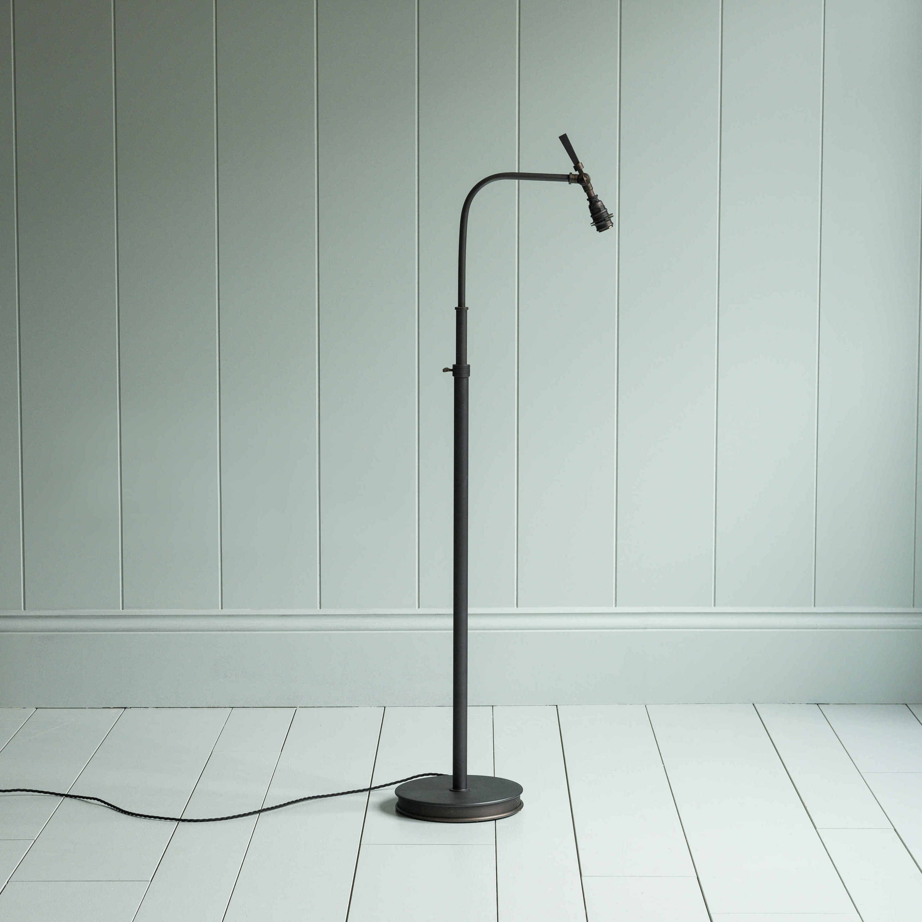  A black floor lamp with a cord lying on the floor. 