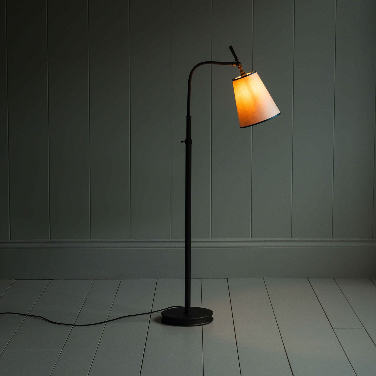 A lamp on a wooden floor in a room.