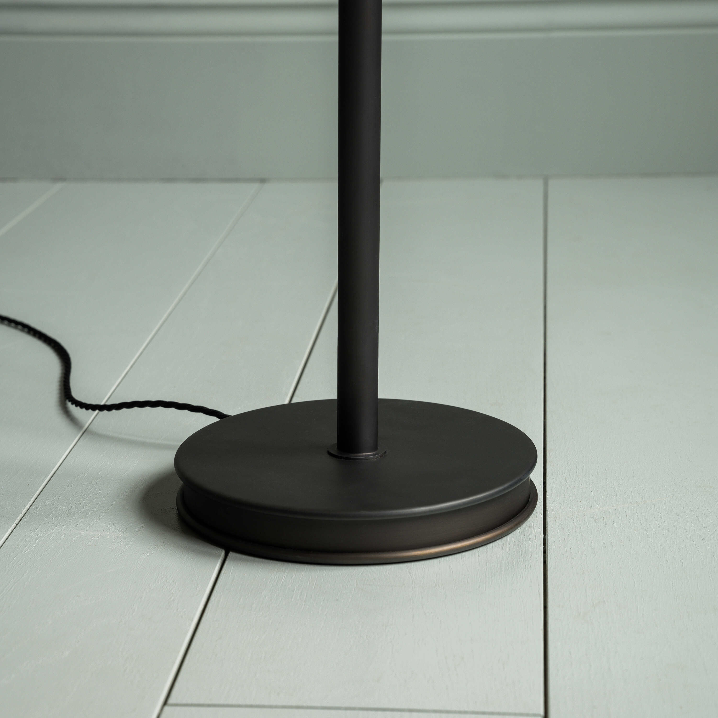  Black floor lamp standing on wooden floor. 