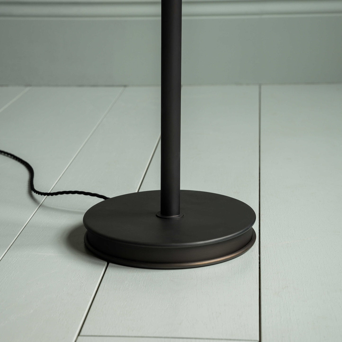 Black floor lamp standing on wooden floor.