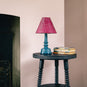 Ditsy Classic Empire Lamp Shade in Dotty Maroon, With Ditsy Ceramic Table Lamp Base in Turquoise On a Spindle Side Table, Carbon Black, With Bunch of Books - Nicola Harding 