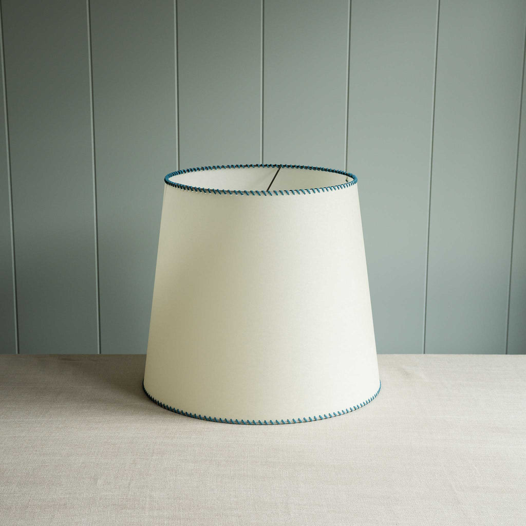  A white lamp shade accented with blue stitching, perfect for contemporary interiors. 