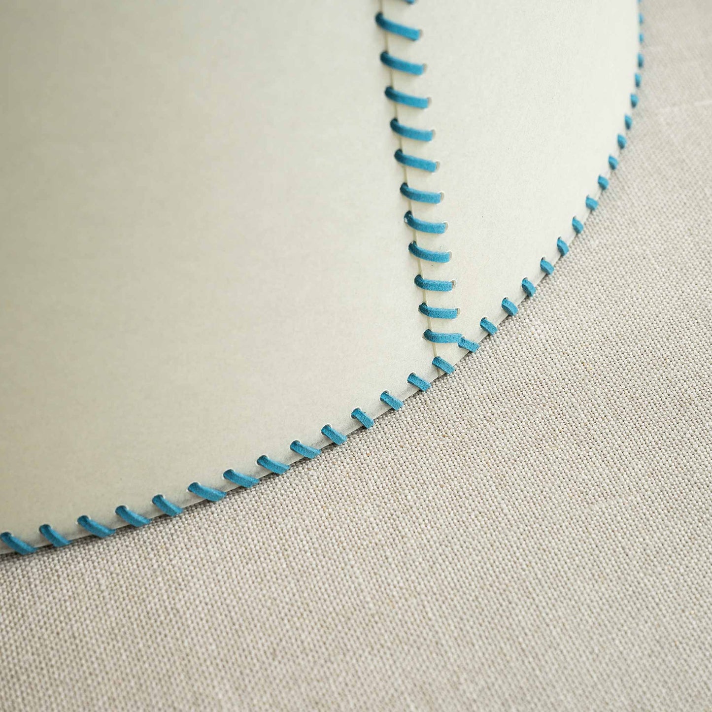 A close-up of a lampshade with blue stitching, adding a touch of elegance and style to any room decor.