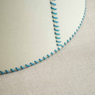  A close-up of a lampshade with blue stitching, adding a touch of elegance and style to any room decor. 