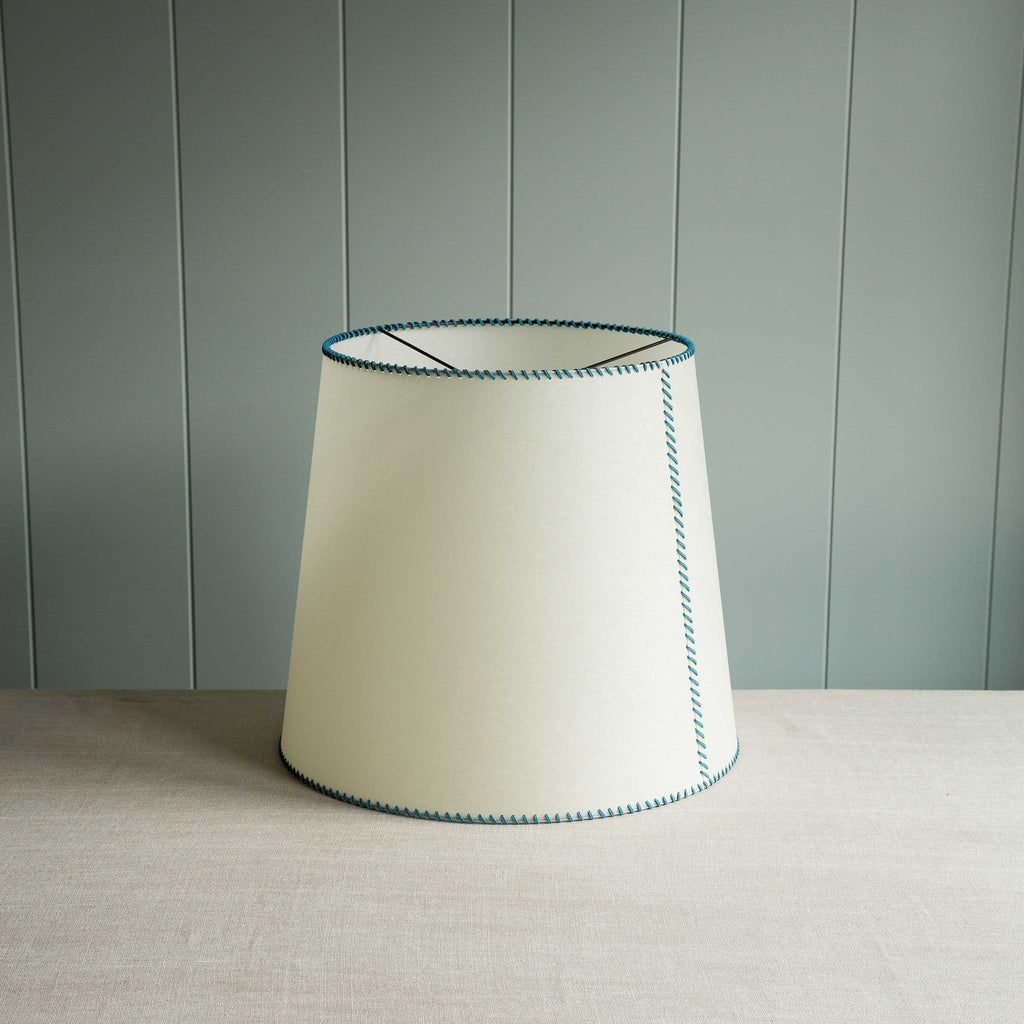  White lamp shade with blue stitching, adding a touch of color to any room decor. 