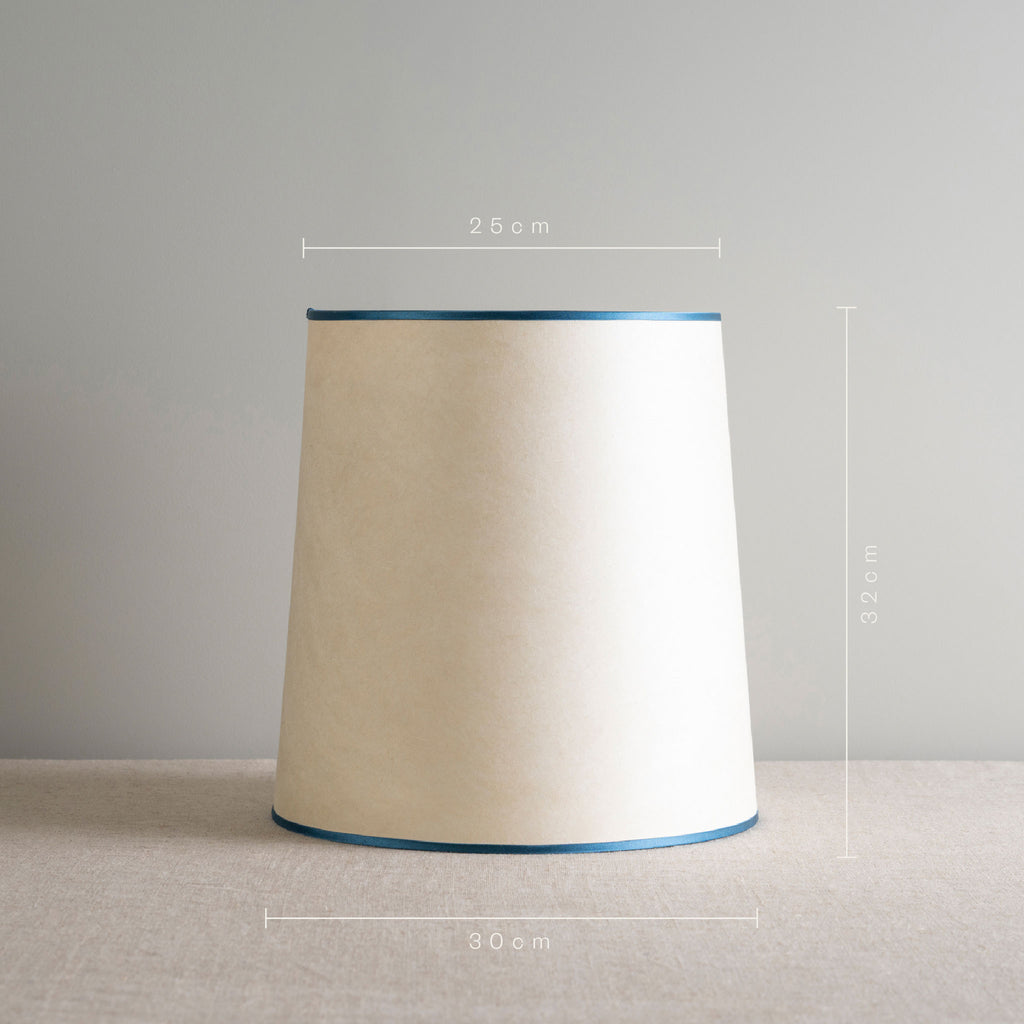  A lamp shade with a blue band on top, adding a touch of color to the overall design. 