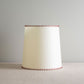 White lamp with red stitching detail, adding a pop of color to the sleek design.