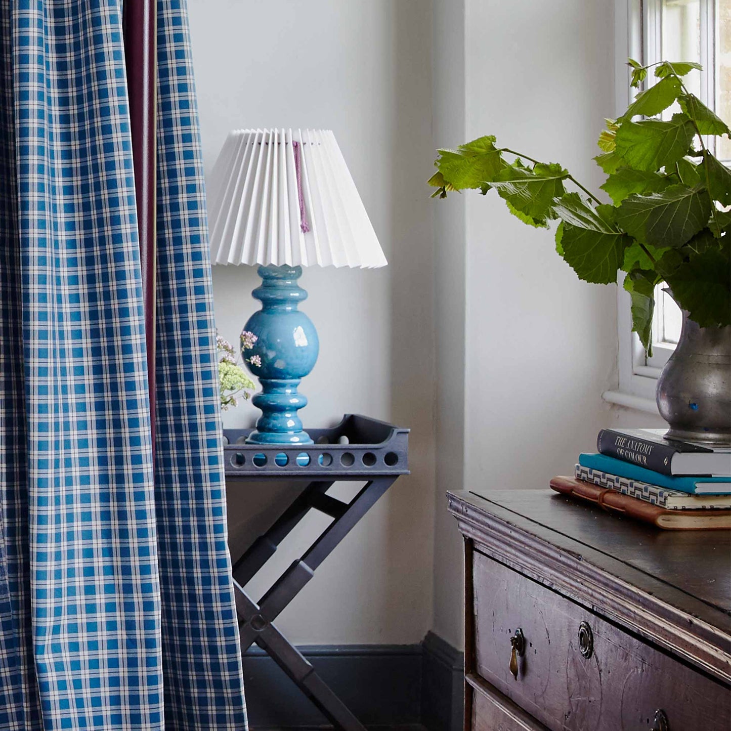 Blue and white checkered curtain hanging in front of lamp.