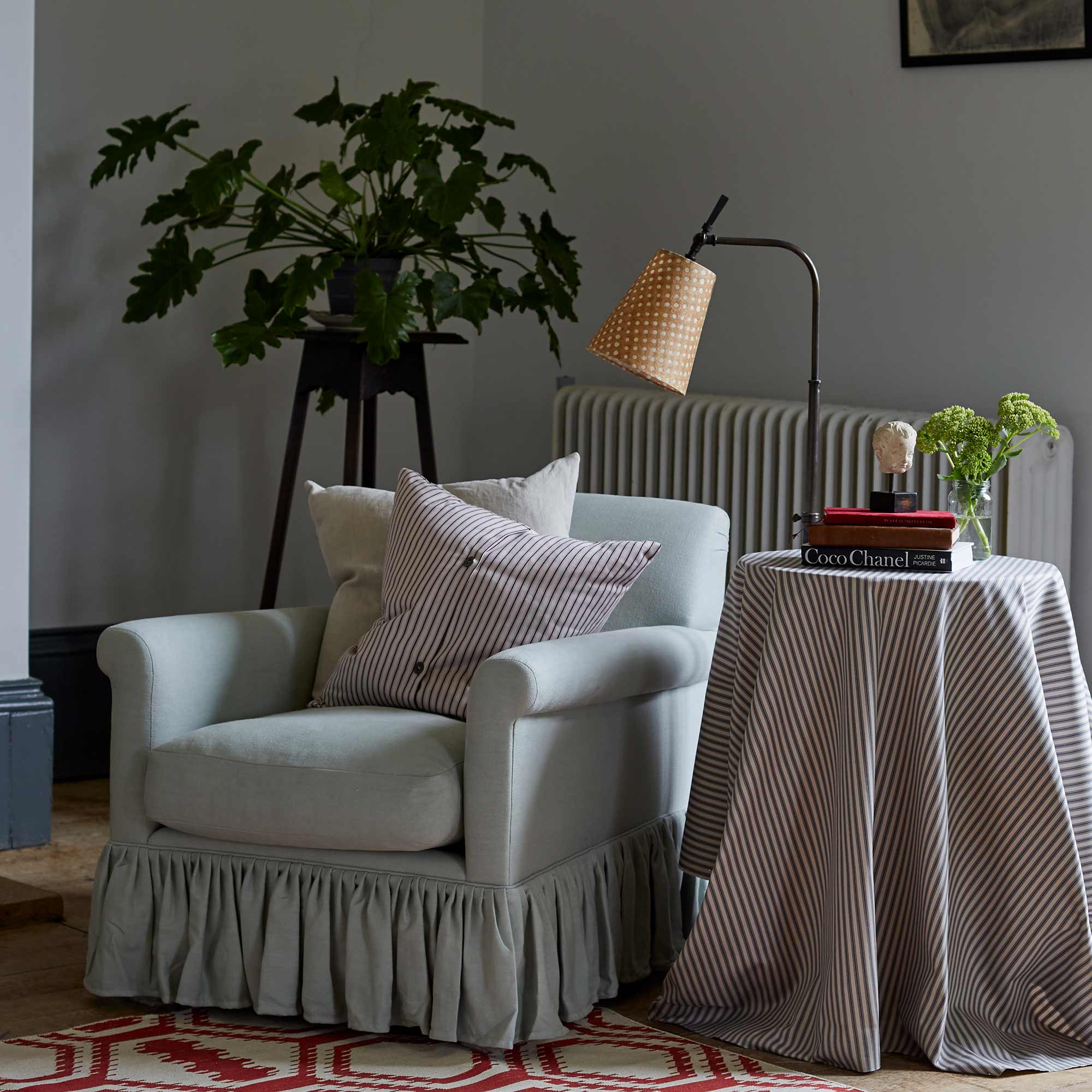  To The Point Batik Paper Empire Lamp Shade in Spotty Dotty Tan, With Waxed Brass Floor Lamp, Beside the Armchair with Cushions and a Side Table with books - By NiX 