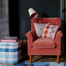 Brass Waxed Floor Lamp with To The Point Paper Empire Lamp Shade in Soft White with Peacock Blue Trim, next to an Ottoman with books and Armchair With Cushions - NiX by Nicola Harding & Co.